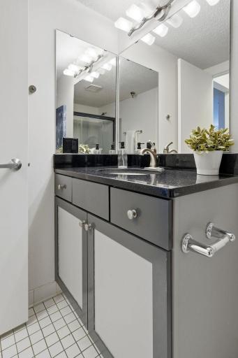 Bathroom vanity offers granite countertop space and convenient storage below.