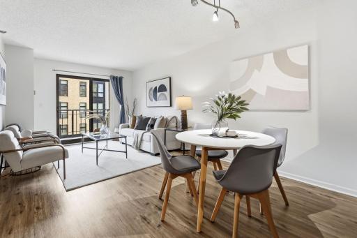 Open-concept living and dining area with wood flooring and access to the private balcony.