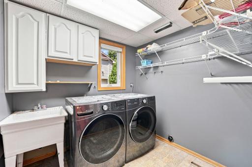 Main level laundry room with storage and utility sink