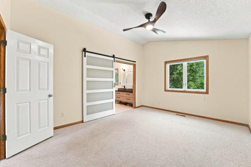 Primary bedroom with attached primary bathroom and walk-in closet