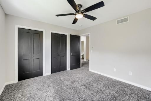 Primary bedroom with ceiling fan and two closets