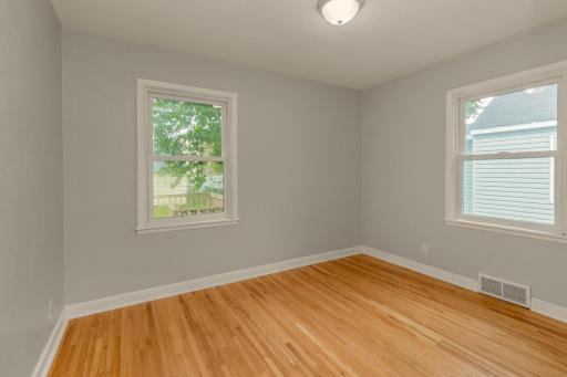 Bedroom two of three sits on the main floor and is flooded with natural light and has hardwood floors