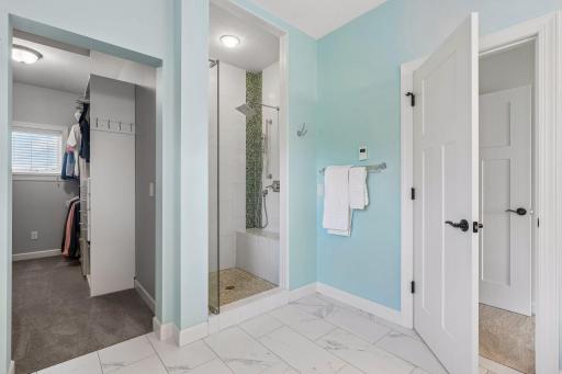 Walk-in fully tiled shower, with bench, along with secondary hand-held shower head and frameless shower door. Custom closet system in the closet provides lots of usable hanging space.