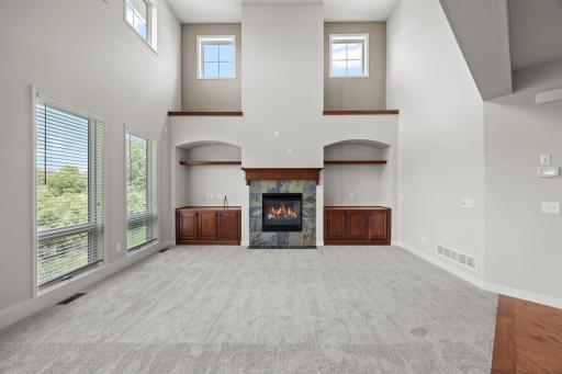 A gas fireplace with tile surround, built-in cabinetry, and soft carpeting add warmth while keeping the premium views in focus.
