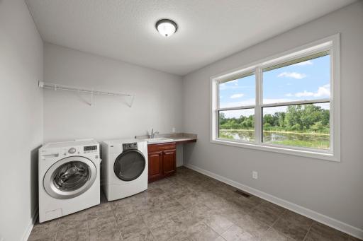 The spacious laundry room features a utility sink, built-in cabinetry, and ample counter space, providing plenty of room for crafts, hobbies, or additional workspace.