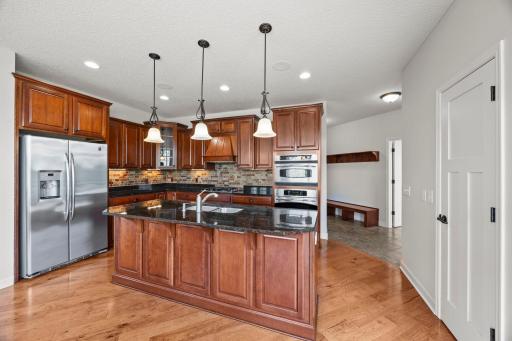 Cherry cabinetry, granite countertops, hickory flooring, stainless steel appliances, under-cabinet lighting, and a tile backsplash bring richness and texture throughout.