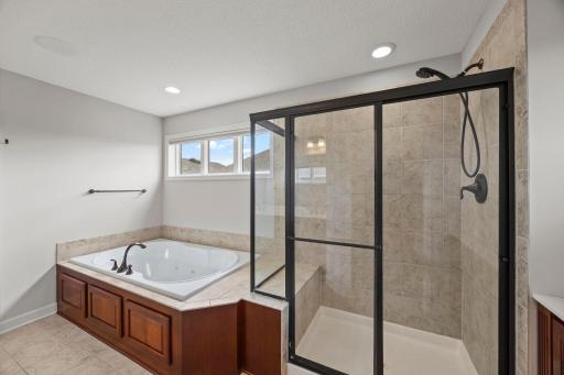 Private bathroom with jetted soaking tub and tiled walk-in shower.
