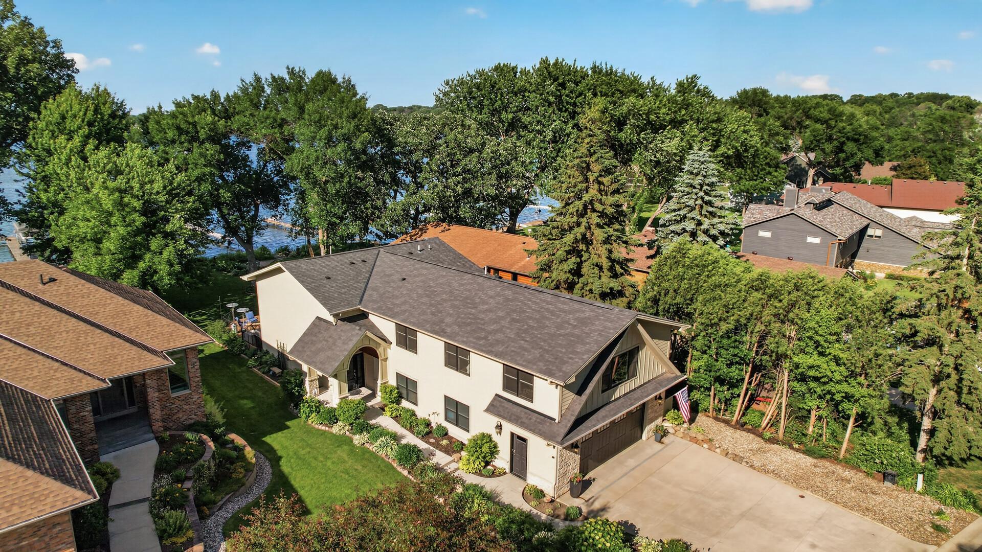 Nestled among mature trees and lush greenery, this lakeside home creates an unforgettable first impression.