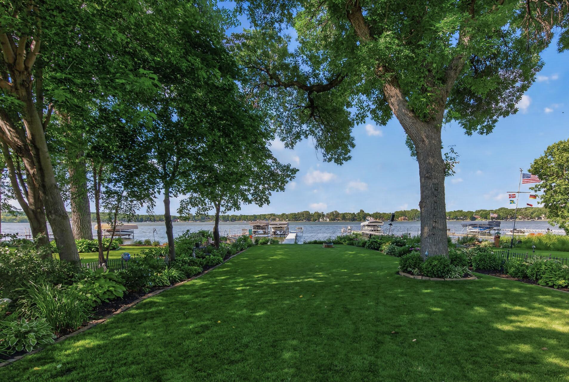 This picturesque lakeside setting offers a flat lot, towering shade trees, and manicured grounds.