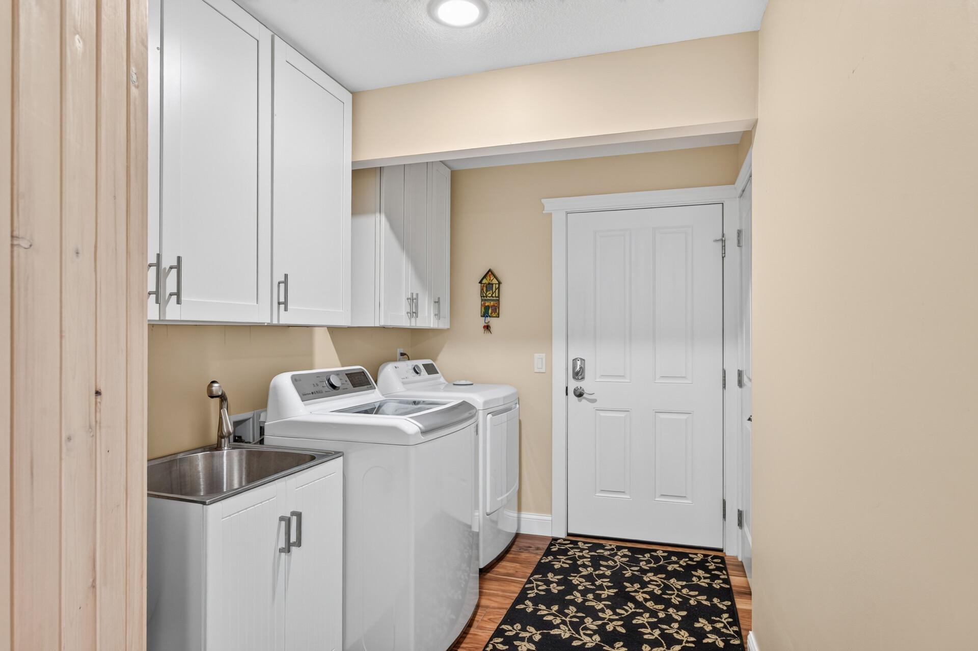 The convenient main level laundry room features built-in cabinetry, a utility sink, and direct access to the attached garage.