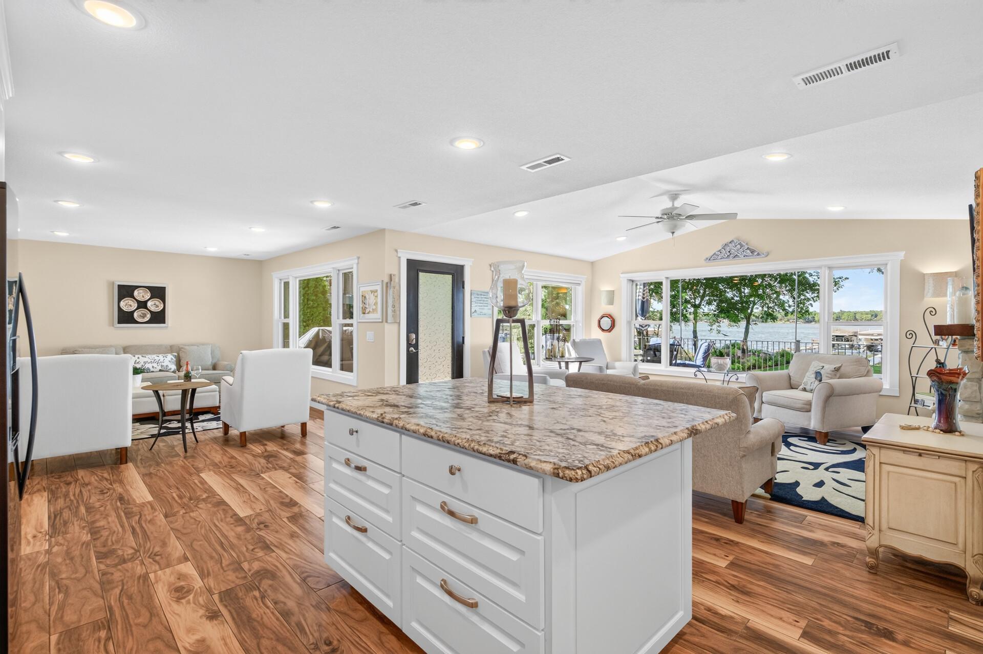The oversized kitchen island anchors this open-concept living space, where expansive windows showcase breathtaking views of the lake.