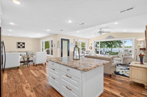 The oversized kitchen island anchors this open-concept living space, where expansive windows showcase breathtaking views of the lake.