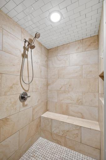 The primary shower offers floor-to-ceiling tile and a built-in bench. This steam shower penetrates tight muscles, decreases stiffness, and can soothe soreness.