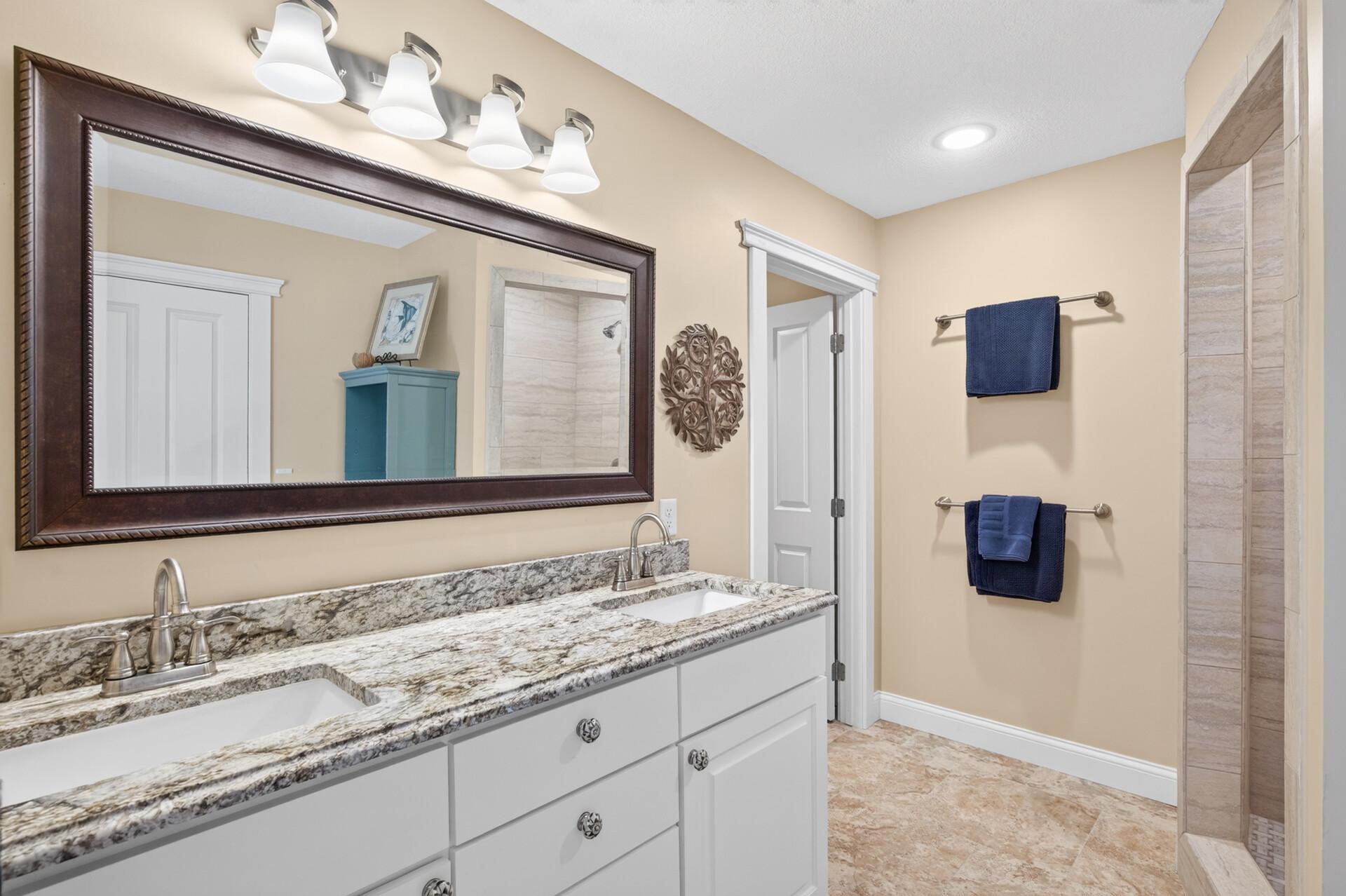 The Jack-and-Jill bathroom features dual sinks, leathered granite countertops, and a beautifully tiled walk-in shower.