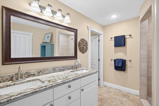 The Jack-and-Jill bathroom features dual sinks, leathered granite countertops, and a beautifully tiled walk-in shower.