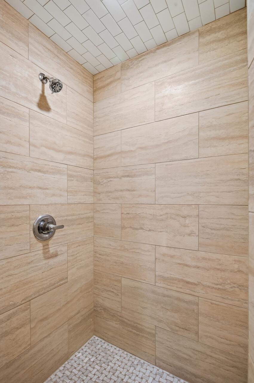 The walk-in shower in the Jack-and-Jill bathroom features floor-to-ceiling tile and timeless, spa-inspired finishes.
