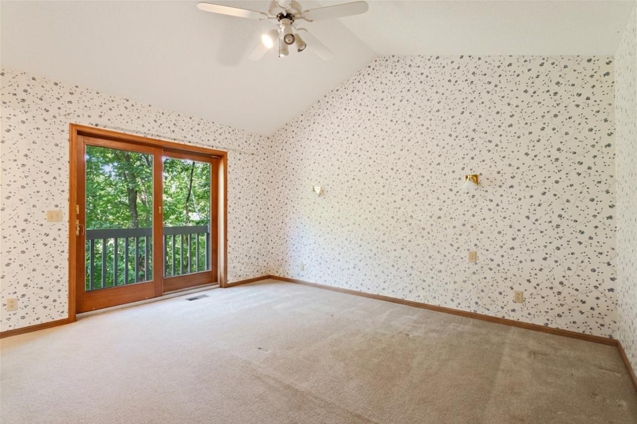 Master bedroom is vaulted, with balcony overlooking wooded ravine setting