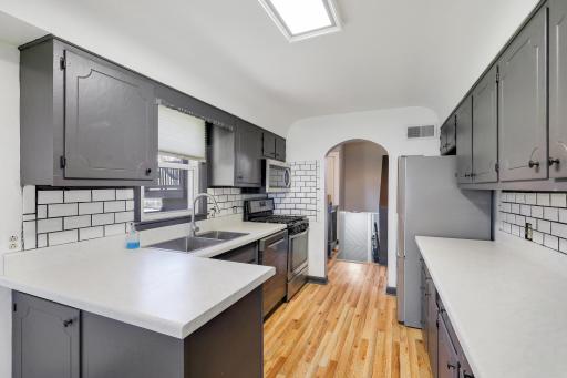 Stainless steel appliances in kitchen with wood floors.