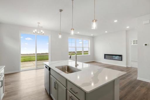The big island features quartz countertops, a deep sink and trash/recycling center cabinet.