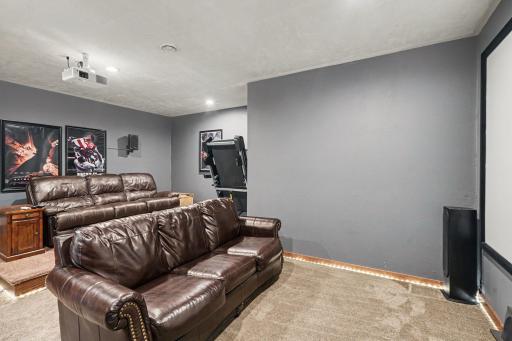 Lower level theater room with tiered seating, a projection screen, and supplemental heat.