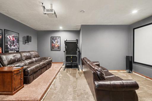 Wide angle of the lower level theater room showing full seating capacity and screen setup.