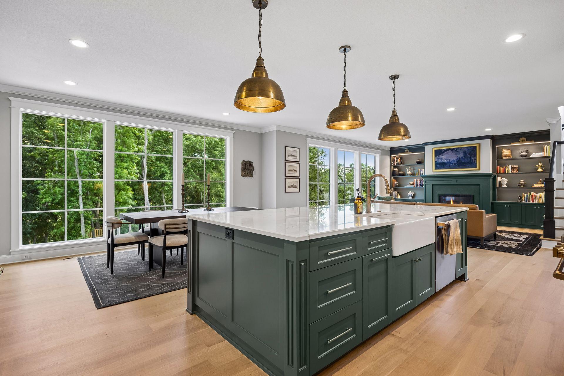 The oversized island becomes the natural gathering place, framed by panoramic woodland views beyond.