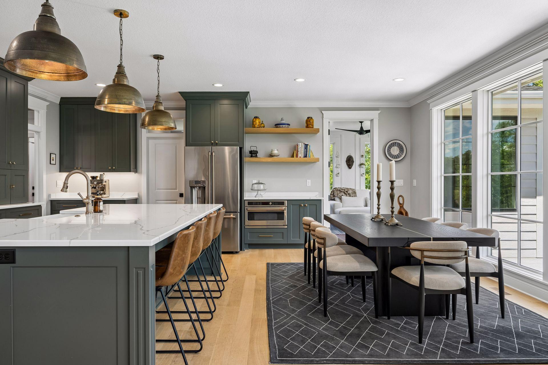 Walls of windows flood the dining area with natural light while seamlessly connecting the kitchen to the surrounding wooded landscape.