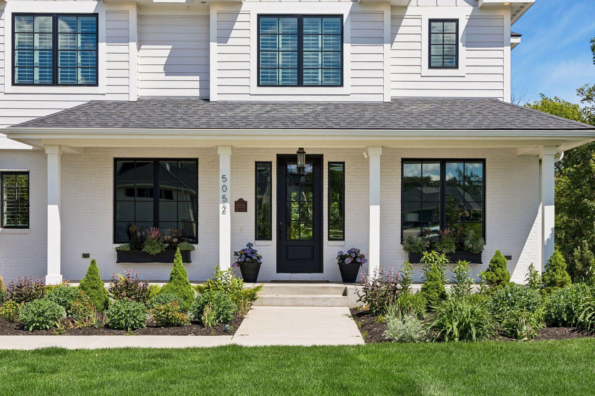 The inviting covered front porch offers a warm welcome with professionally designed landscaping and charming window boxes.