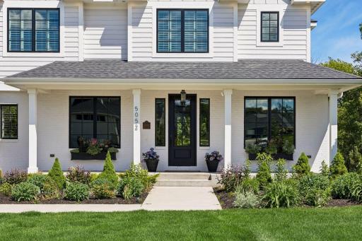 The inviting covered front porch offers a warm welcome with professionally designed landscaping and charming window boxes.