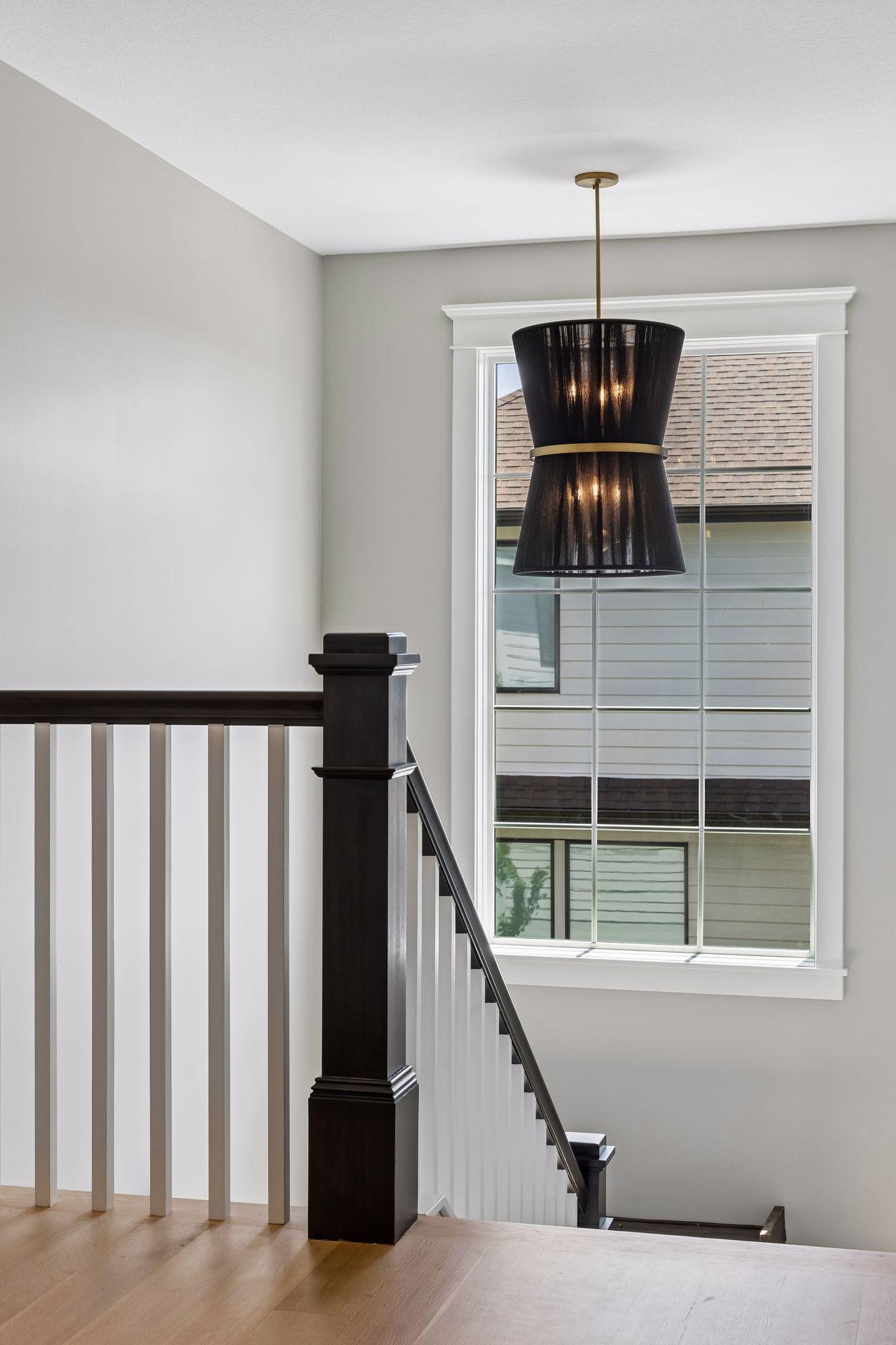 Oversized windows and custom lighting transform the staircase into an architectural focal point.