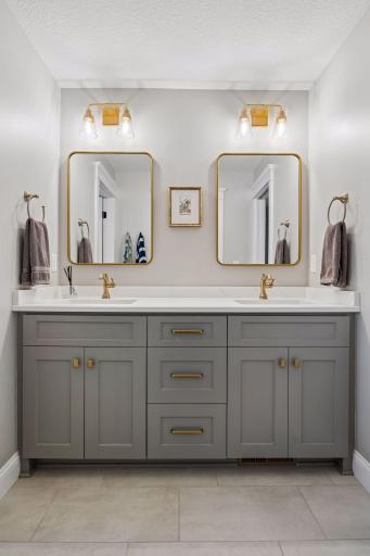 Custom cabinetry, quartz countertops, and elegant brass fixtures elevate this beautifully appointed shared bath.