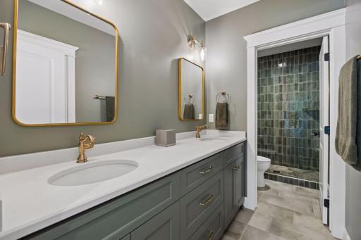 Custom cabinetry, quartz countertops, designer lighting, and elegant finishes create a bathroom that rivals many primary suites.