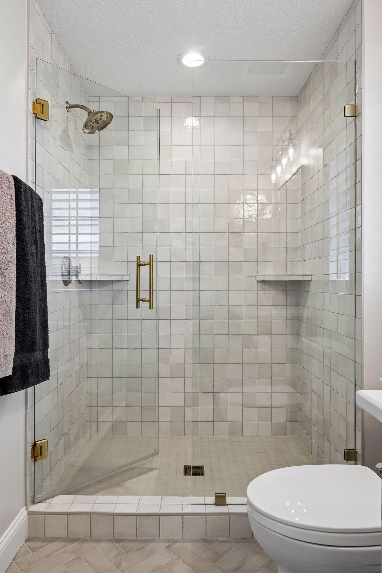 A spacious walk-in shower wrapped in artisan tile and seamless glass delivers a refined, spa-inspired experience.