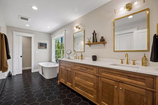 A spa-inspired bath featuring custom walnut cabinetry, quartz surfaces, designer lighting, and a luxurious freestanding soaking tub.