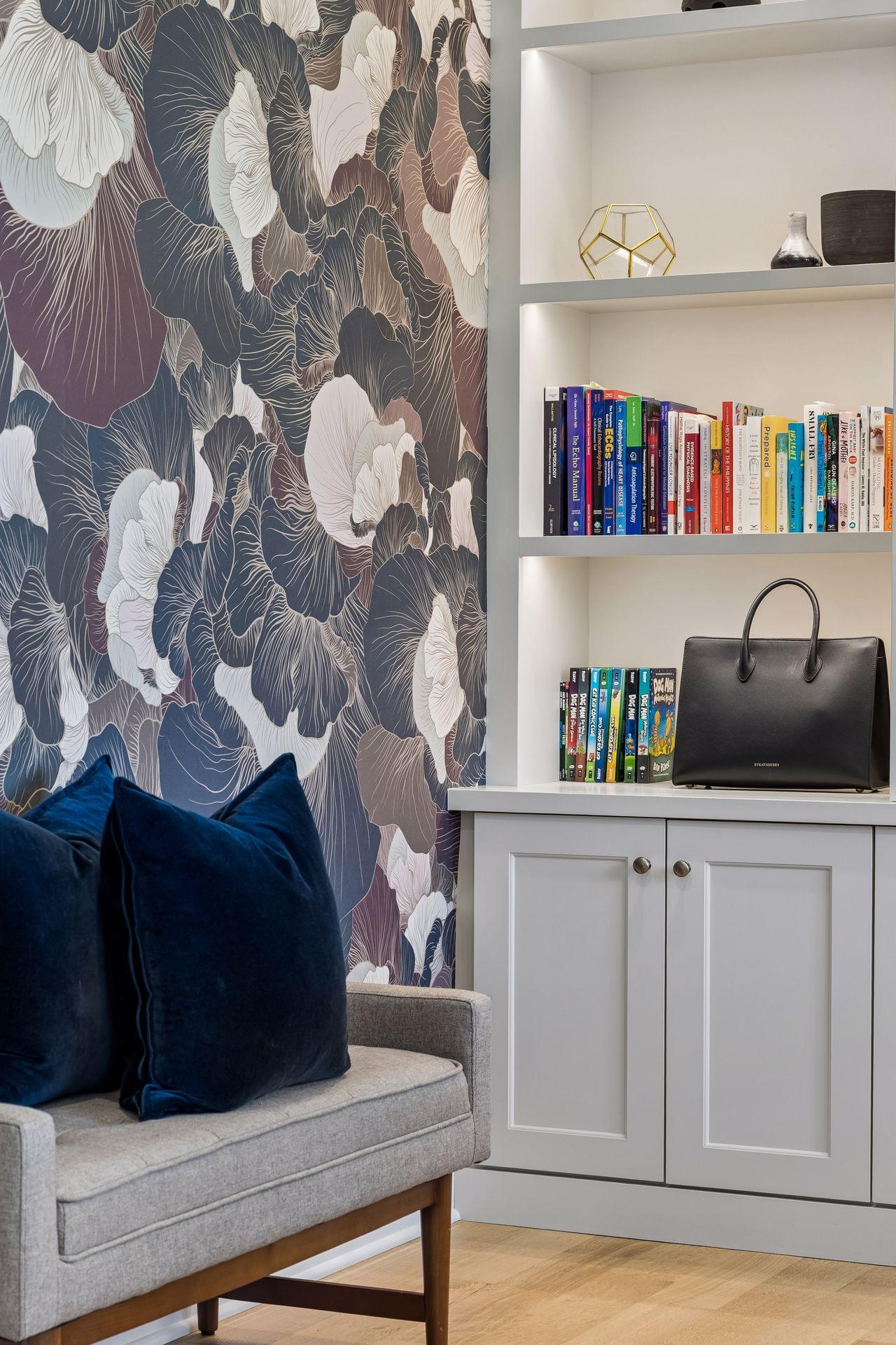 Designer wallpaper, illuminated shelving, and bespoke cabinetry create a workspace that feels equal parts library and private gallery.