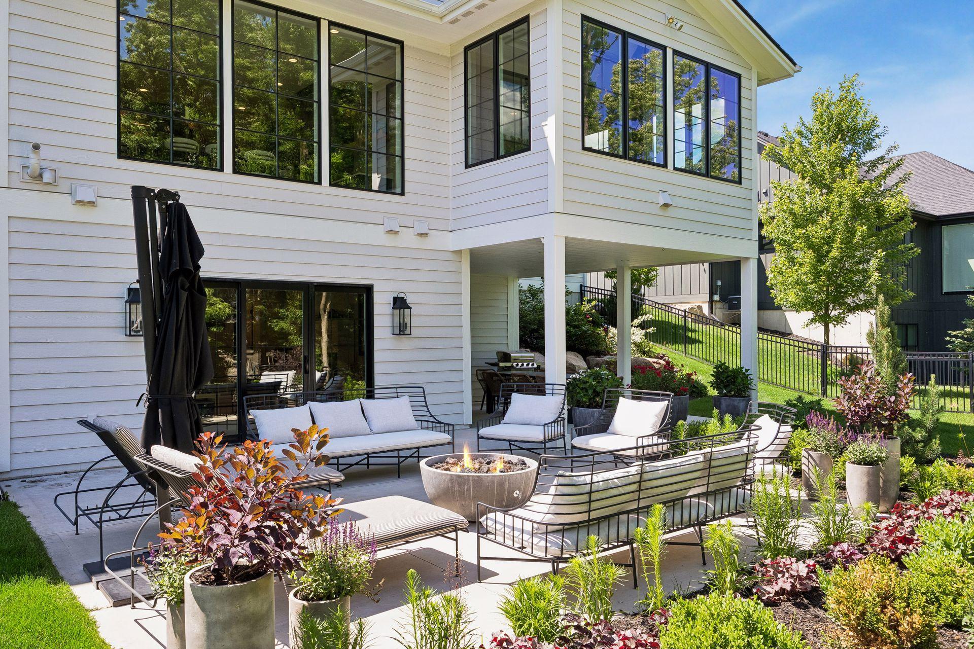 A professionally designed patio creates multiple gathering spaces for entertaining, dining, and relaxing around the fire.