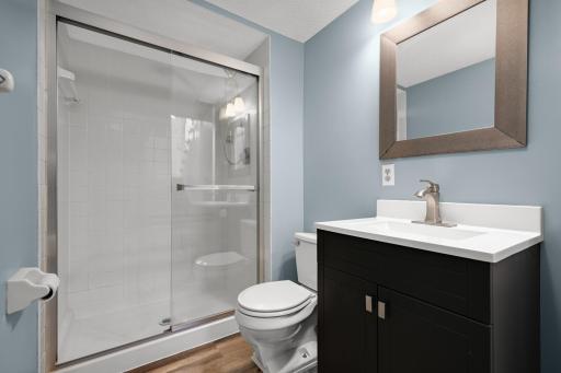 Lower-level Â¾ bathroom featuring a spacious shower and modern vanity with storage.