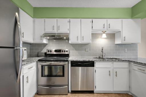 Updated kitchen featuring granite countertops, stainless steel appliances, subway tile backsplash, and ample cabinet and prep space.