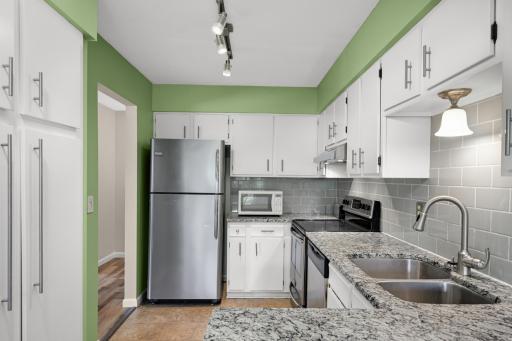 Updated kitchen featuring granite countertops, stainless steel appliances, subway tile backsplash, and generous prep space.