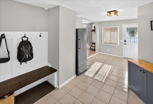 Step into a welcoming, spacious foyer highlighted by ceramic tile flooring and a built-in bench with hooks, offering both style and function, and providing seamless access to the backyard oasis.