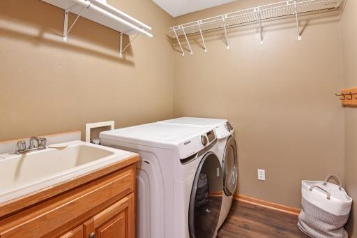 The main floor laundry room offers a laundry sink and shelving with hanging rod~open to garage entrace creating the ideal mudroom!