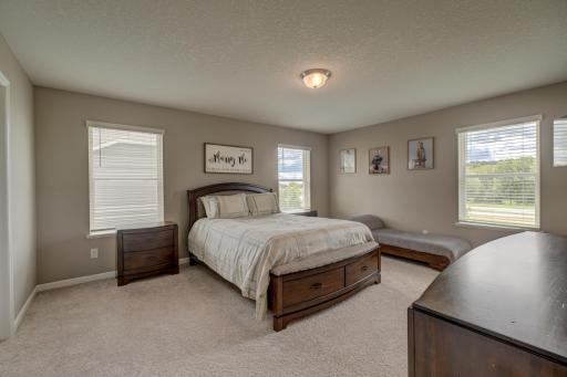 A spacious primary suite with a massive walk-in closet and a private bath featuring double vanities, a soaking tub, and a walk-in shower.