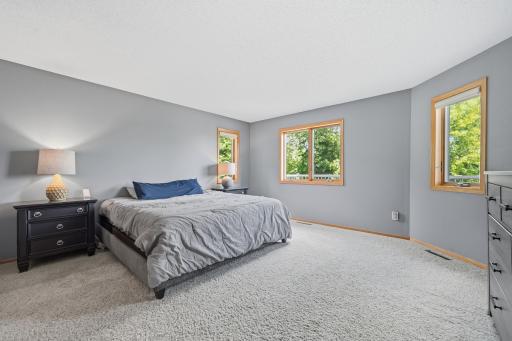 The spacious primary bedroom, located on the main level, offers a peaceful retreat, filled with abundant natural light and calming neutral tones.