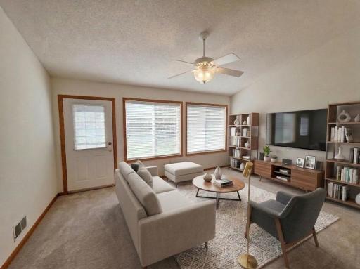 Bright and welcoming sunroom with large windows, plush carpeting, and comfortable gathering space.
