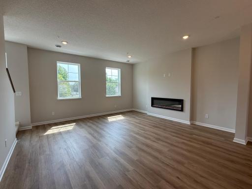 This spacious living room has excellent scenery featuring large windows, a fireplace, and enough space for even the biggest couches.