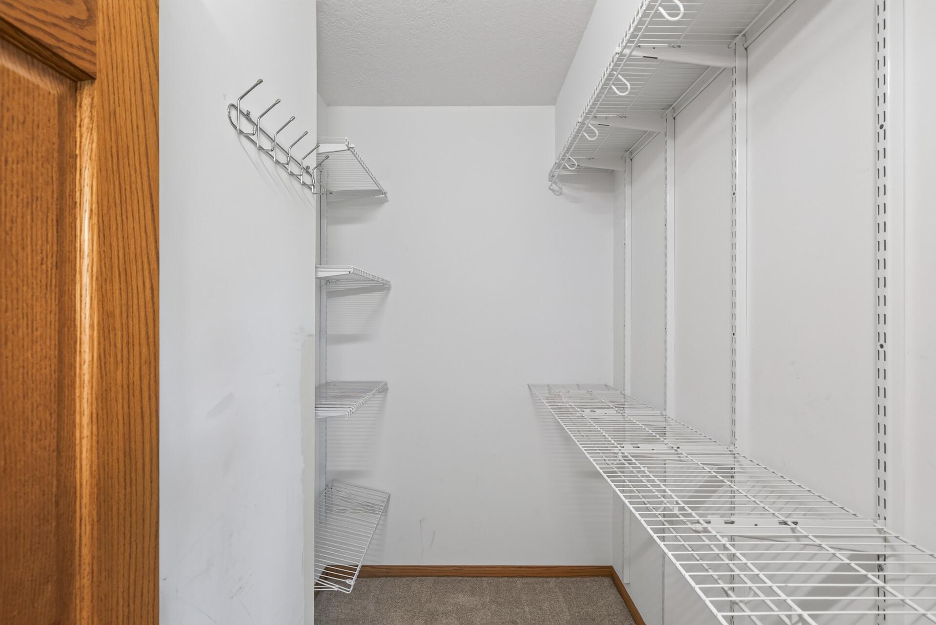 Primary bedroom walk-in closet with shelving and hanging clothes area.