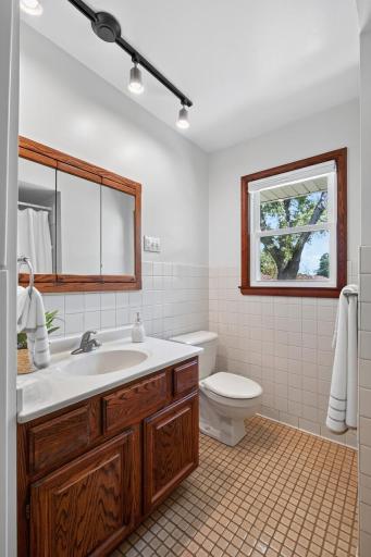 Main-level full bathroom with classic tile and warm wood cabinetry.