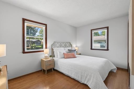 Second main-level bedroom with hardwood floors and two windows.