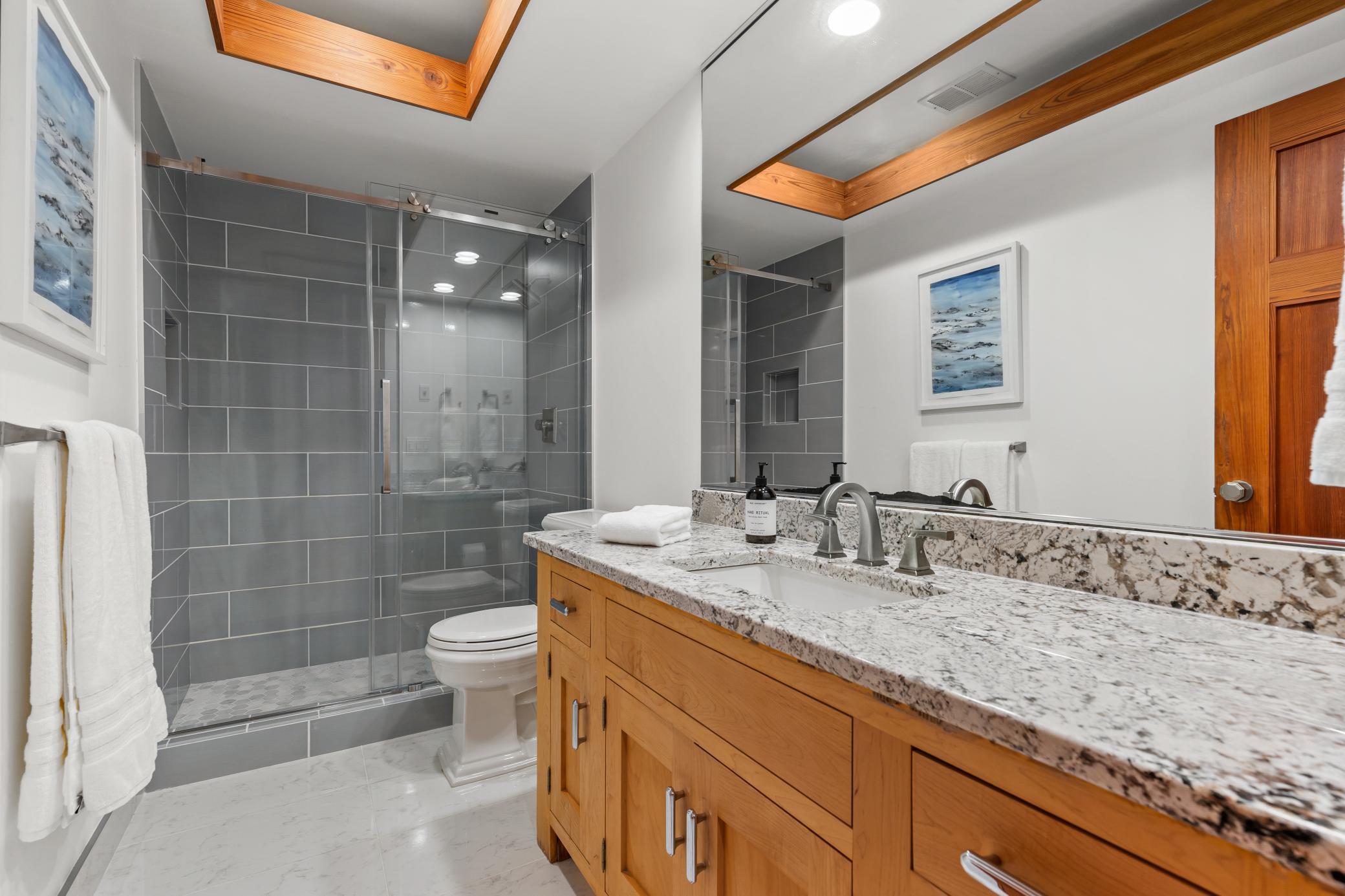 Quartz countertops and freshly tiled bathroom ensuite with lower level bedroom