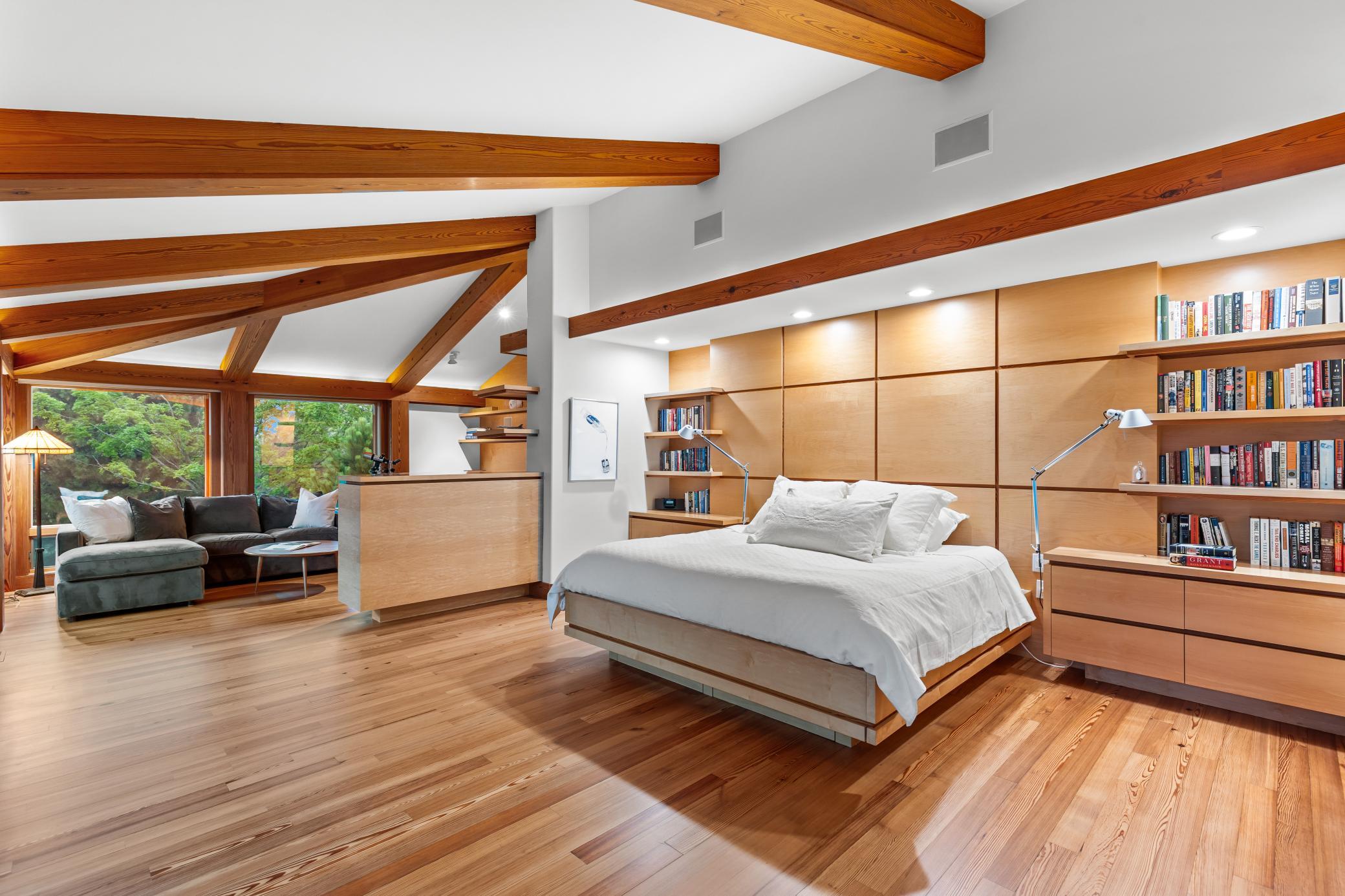 Built-in book cases, soft lighting, and serene views surround this primary suite